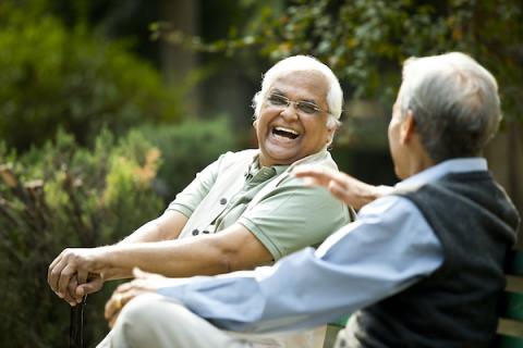 Two friends sitting on a bench outside talking