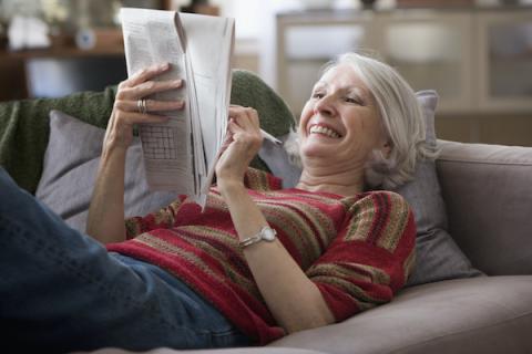 Woman lying on a couch doing a crossword puzzle
