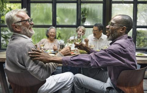 Two men clinking wine glasses together 