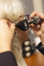 Audiologist checking for hearing loss with an otoscope