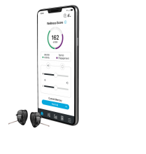 Smart phone with hearing aid app beside a pair of hearing aids