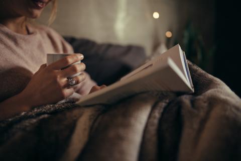 Woman snuggled into a blanket reading a good book